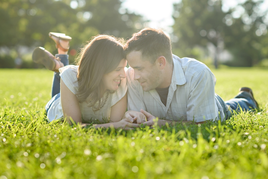A cute couple lay in the grass in penn treaty park.